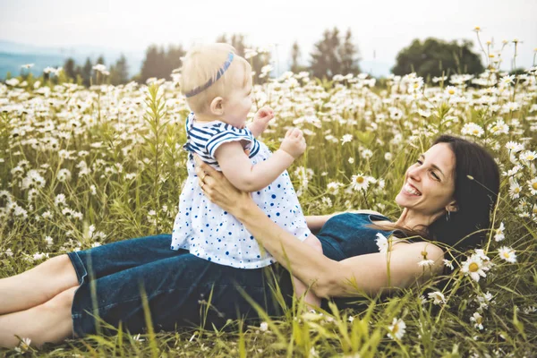 Menina e sua mãe desfrutando ao ar livre no campo de flores da margarida — Fotografia de Stock