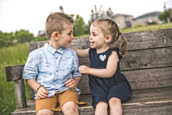 Zwei süße Kinder spielen im grünen Gänseblümchen-Feld — Stockfoto