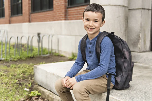 Портрет симпатичного мальчика с рюкзаком перед школой — стоковое фото