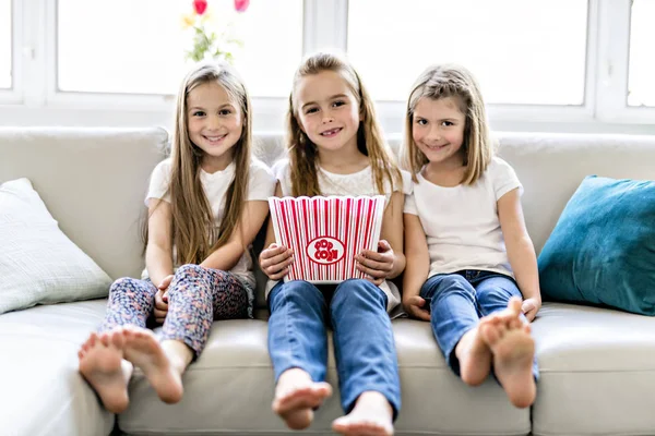 Joyeuses petites filles regardant un film comique à la télévision et mangeant du pop-corn à la maison — Photo