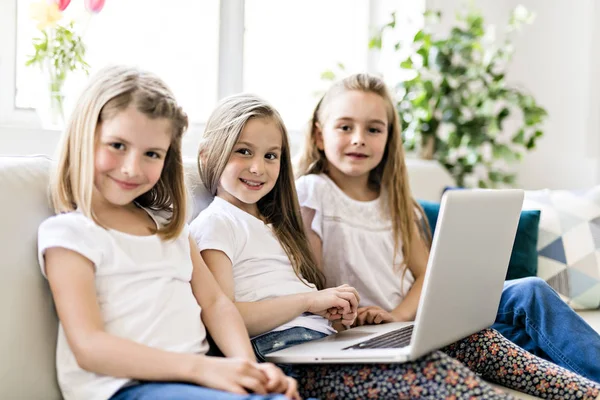 Bonnes petites filles à la maison travaillant avec un ordinateur portable sur le canapé — Photo