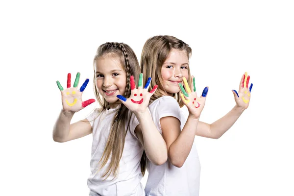 Dos chicas sonrientes con las palmas pintadas por una pintura. Aislado sobre fondo blanco —  Fotos de Stock