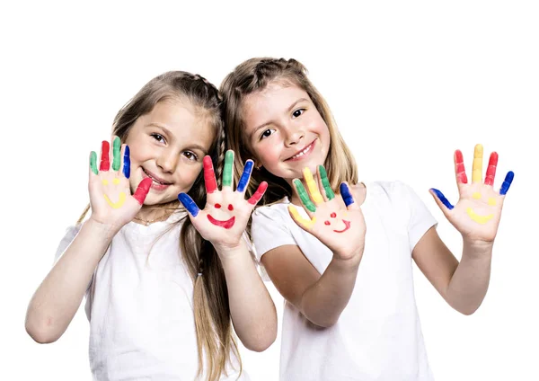 Twee lachende meisjes met de handpalmen geschilderd door een verf. Geïsoleerd op witte achtergrond — Stockfoto