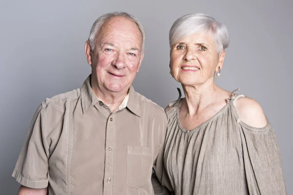 Starší pár pózuje na studio šedé pozadí — Stock fotografie