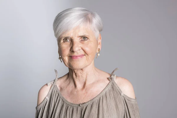 Elderly woman on studio dark gray background — Stock Photo, Image