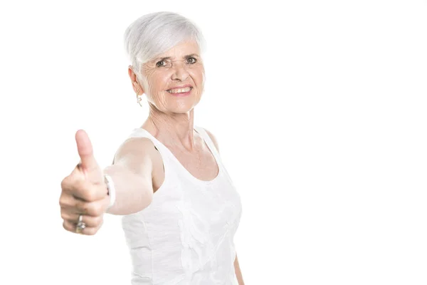 Пожилая женщина на белом фоне студии с большим пальцем вверх — стоковое фото
