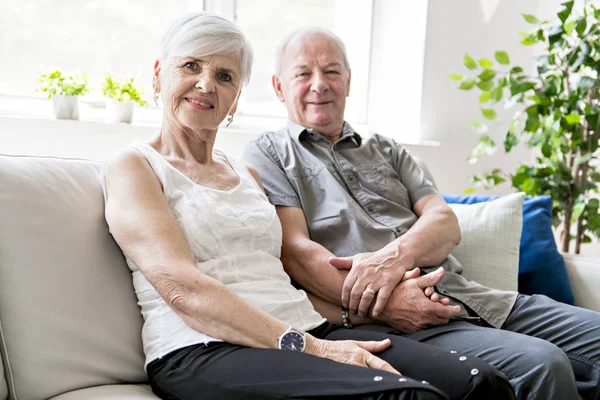 Affectionate attractive elderly couple sitting together on a couch — Stock Photo, Image