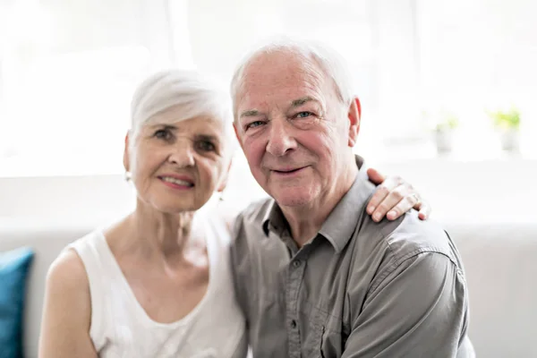 Affectionate attractive elderly couple sitting together on a couch — Stock Photo, Image