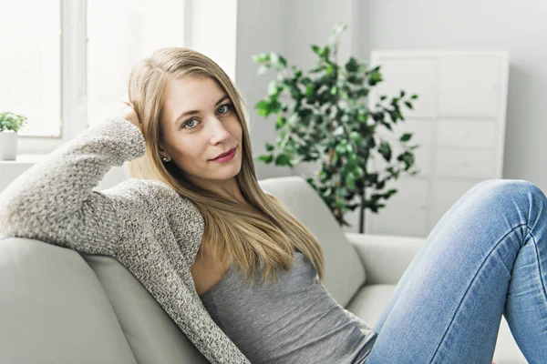 Mujer joven en un sofá en la sala de estar — Foto de Stock