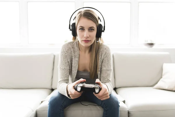 Piękna młoda kobieta siedzi na kanapie z kontrolera gier — Zdjęcie stockowe