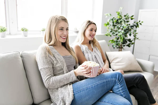 Kaksi ystävää katsomassa elokuvaa kotona popcornilla — kuvapankkivalokuva