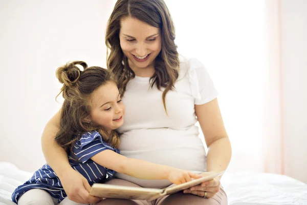 Retrato de uma mãe e filha lendo um livro deitado e relaxar na cama — Fotografia de Stock