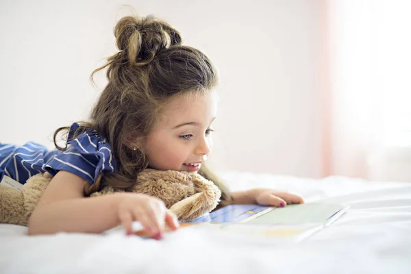 Mała dziewczynka z książką w sypialni — Zdjęcie stockowe
