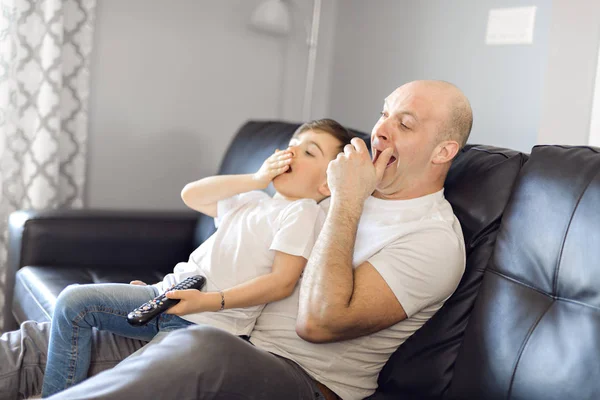 Man and young boy with remote control yawn — Stock Photo, Image