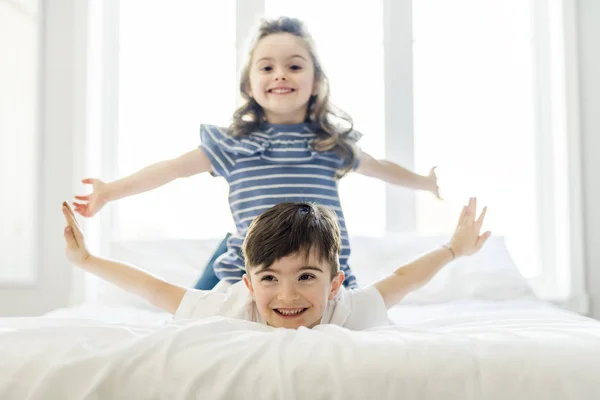 Брат и сестра веселятся вместе на кровати — стоковое фото