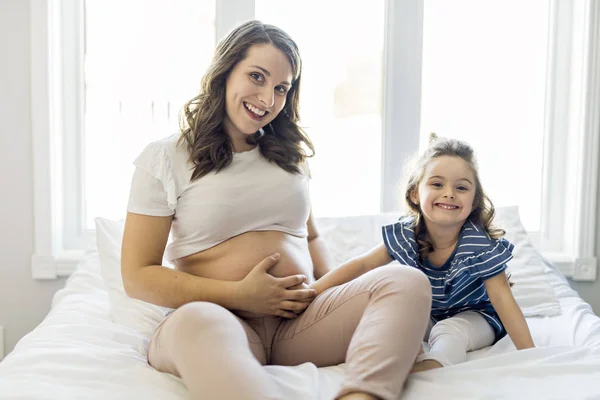 Donna incinta con sua figlia in camera da letto insieme — Foto Stock