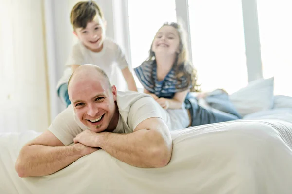 ベッドの上で一緒に楽しいことを子供 2 人幸せな父 — ストック写真