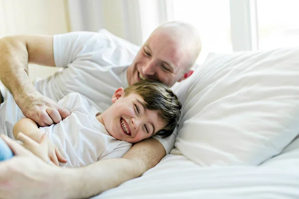 Feliz padre e hijo divirtiéndose juntos en una cama —  Fotos de Stock