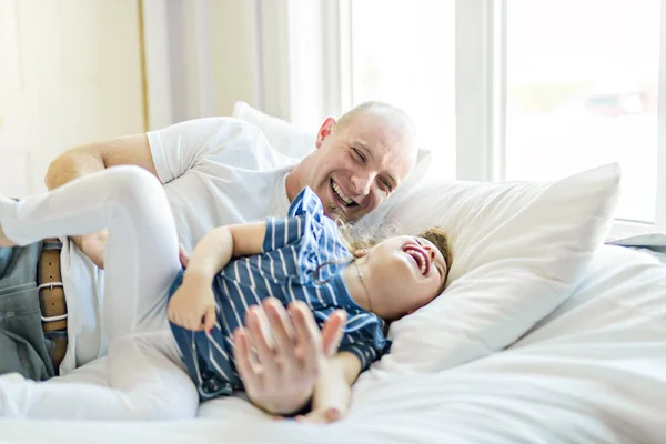 Feliz padre e hija divirtiéndose juntos en una cama — Foto de Stock