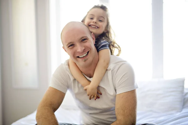 Happy father and daughter having fun together on a bed — Stock Photo, Image