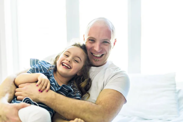 Gelukkig vader en dochter samen plezier op een bed — Stockfoto