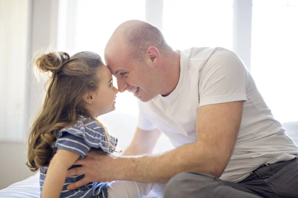 Feliz padre e hija divirtiéndose juntos en una cama — Foto de Stock