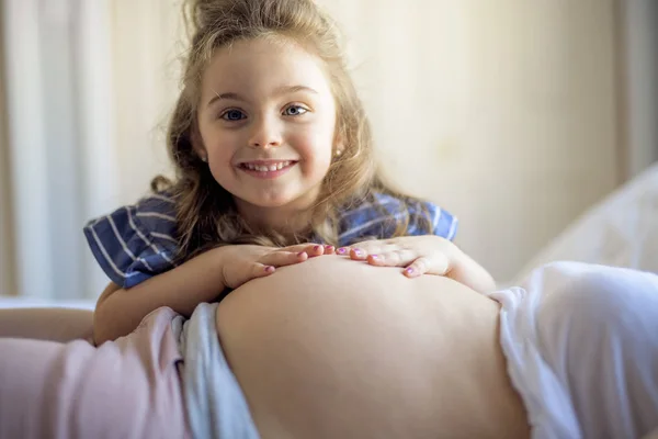 Беременная женщина с дочерью в спальне вместе — стоковое фото