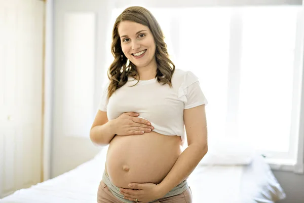 Embarazo, maternidad, mujer embarazada feliz cerca de la ventana en casa —  Fotos de Stock