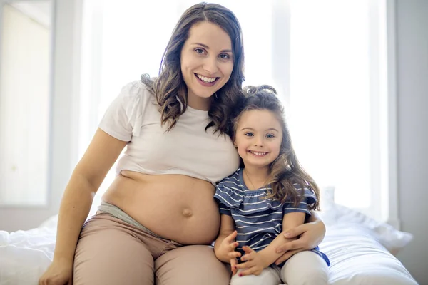 Donna incinta con sua figlia in camera da letto insieme — Foto Stock