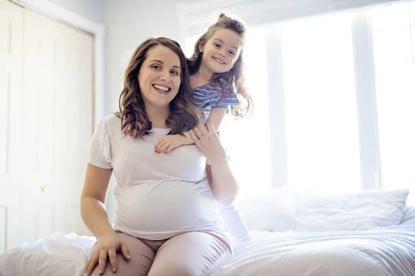 Zwangere vrouw met haar dochter op de slaapkamer samen — Stockfoto