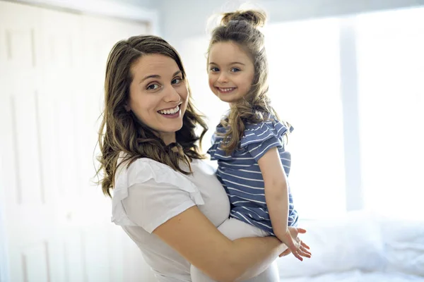 Embarazada con su hija en el dormitorio juntos —  Fotos de Stock