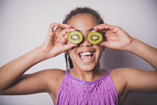 Black girl child with kiwi over the eye — Stock Photo, Image