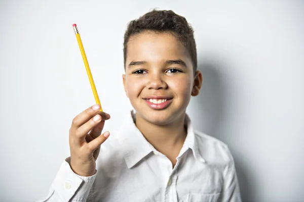 Černý chlapec drží školy pensil nad bílým pozadím — Stock fotografie