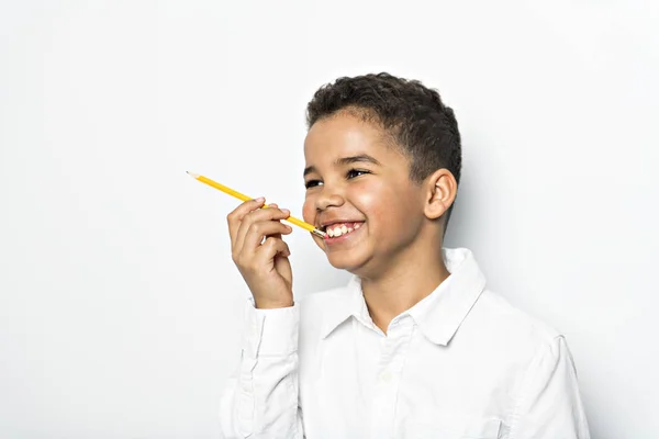 En svart pojke som innehar skolan pensil över vit bakgrund — Stockfoto
