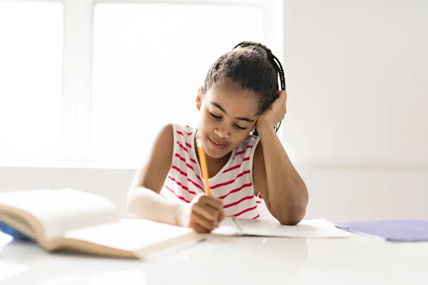 En söt svart tjej gör läxor hemma — Stockfoto