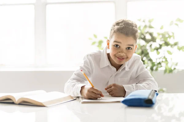 Милый черный мальчик делает домашнее задание дома — стоковое фото