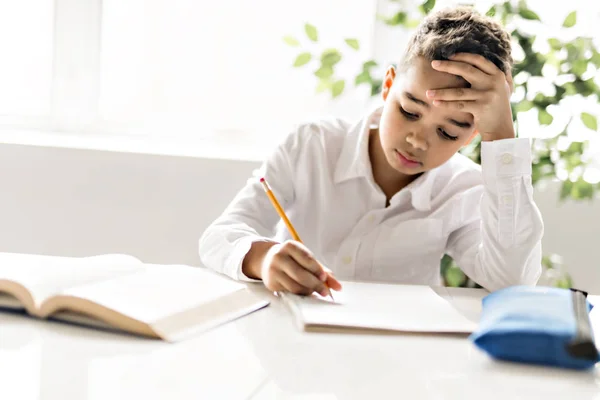 Милий чорний хлопчик робить домашнє завдання вдома — стокове фото