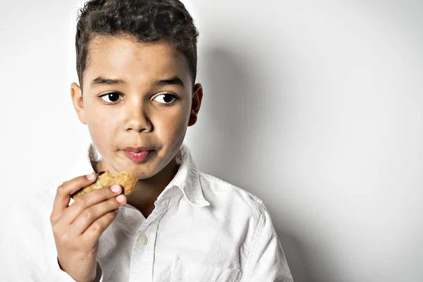 Svart pojke äter cookie över vit bakgrund — Stockfoto