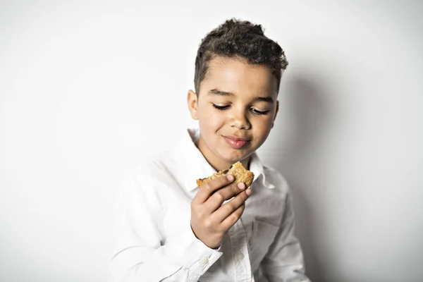 Noir garçon manger cookie sur fond blanc — Photo
