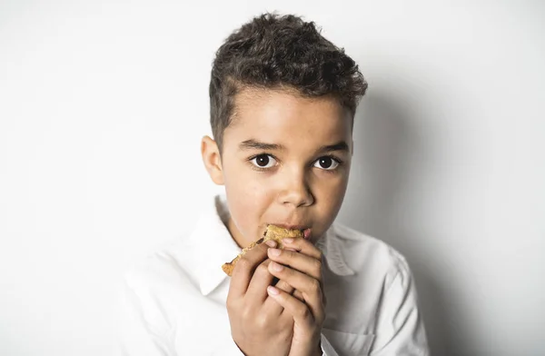 Zwarte jongen eten cookie op witte achtergrond — Stockfoto