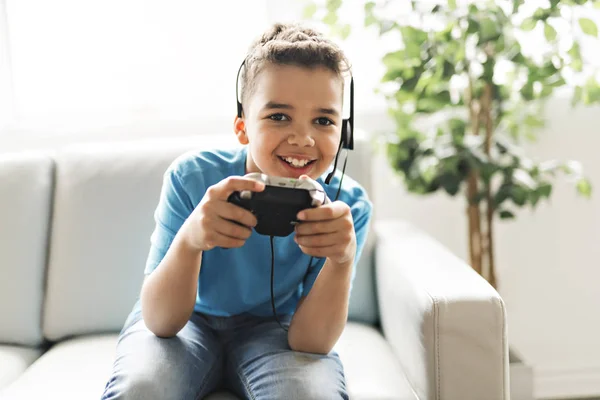 Black boy play video game on sofa with headset — Stock Photo, Image