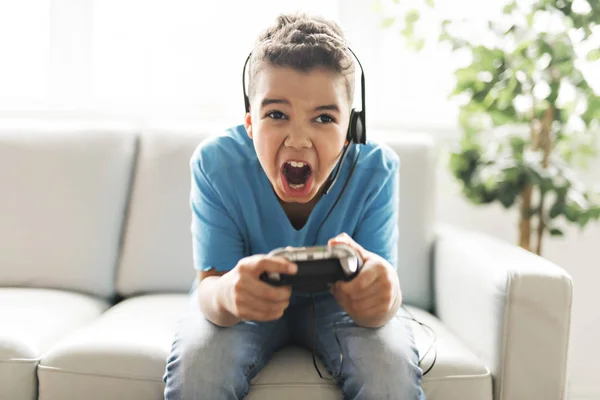 Black boy play video game on sofa with headset — Stock Photo, Image