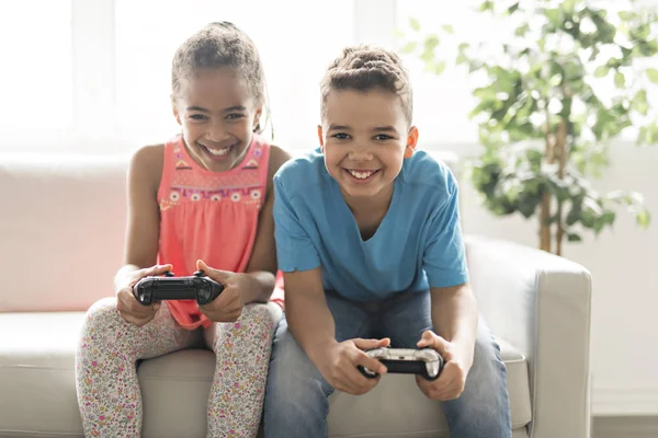 Brother and sister play video game on sofa — Stock Photo, Image