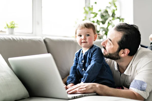 Busy father working on laptop with baby in front