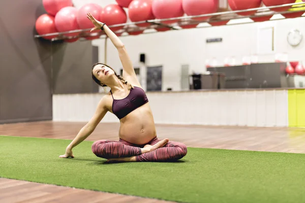 Těhotná žena dělá cvičení v tělocvičně — Stock fotografie
