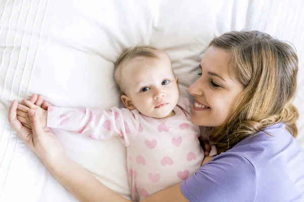 Felice madre con bambino sdraiato sul letto a casa — Foto Stock
