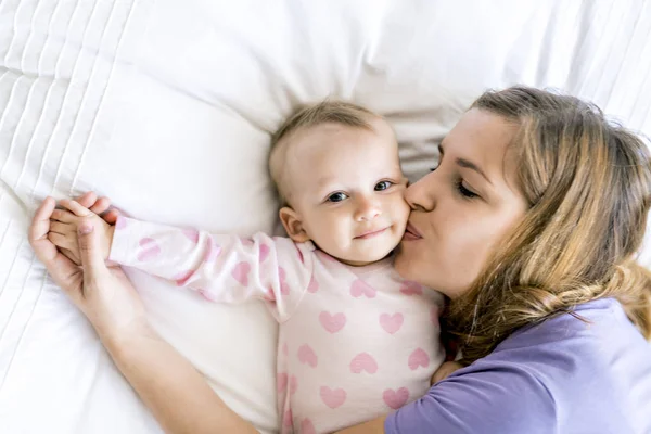 Madre feliz con el bebé acostado en la cama en casa — Foto de Stock