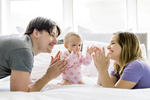 Retrato de hermosos padres jóvenes y lindo bebé en la cama — Foto de Stock