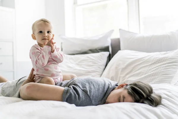 Уставший отец с ребенком, лежащим на кровати дома — стоковое фото