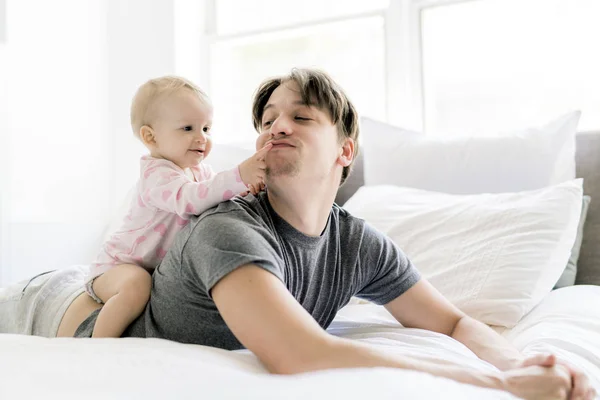 Счастливый отец с ребенком лежит на кровати дома — стоковое фото